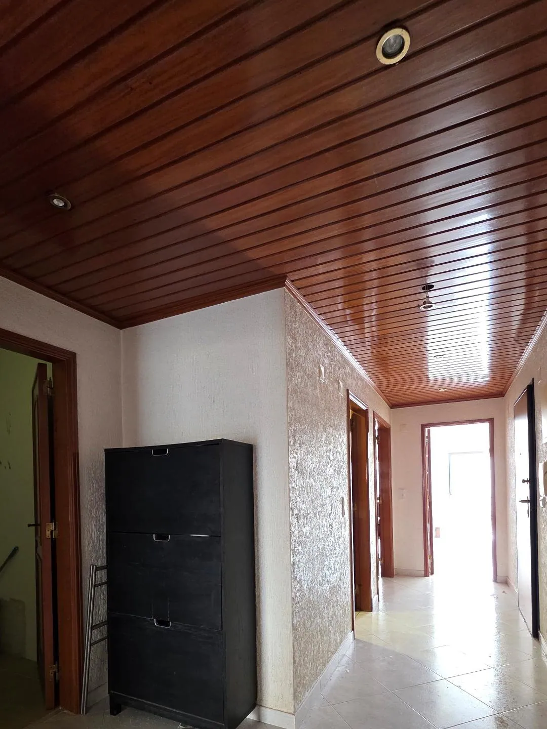 O corredor antes da obra, com teto forrado a madeira.