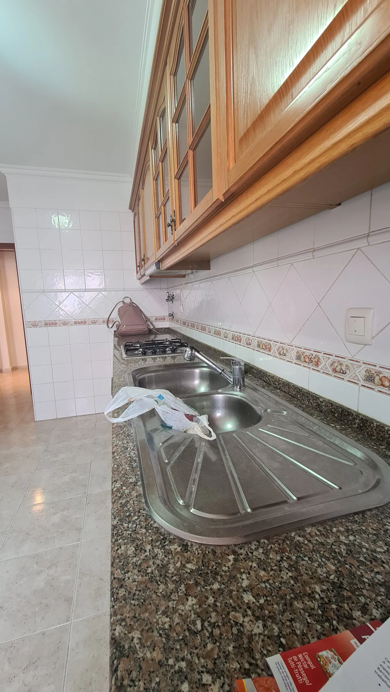 A bancada antiga em granito escuro, com lava-loiça de inox.