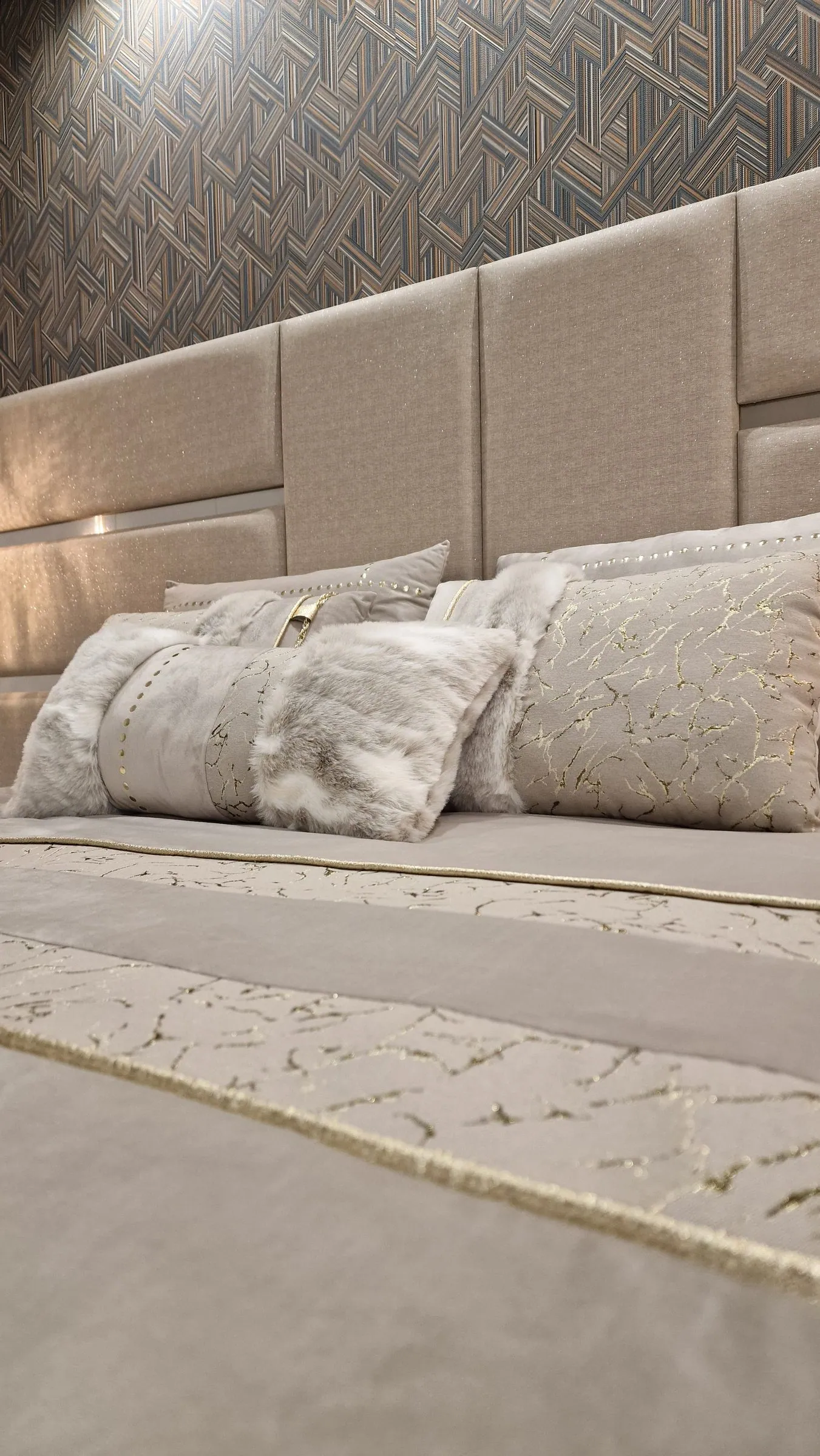 Cama com almofadas e colcha em tons de areia e dourado.