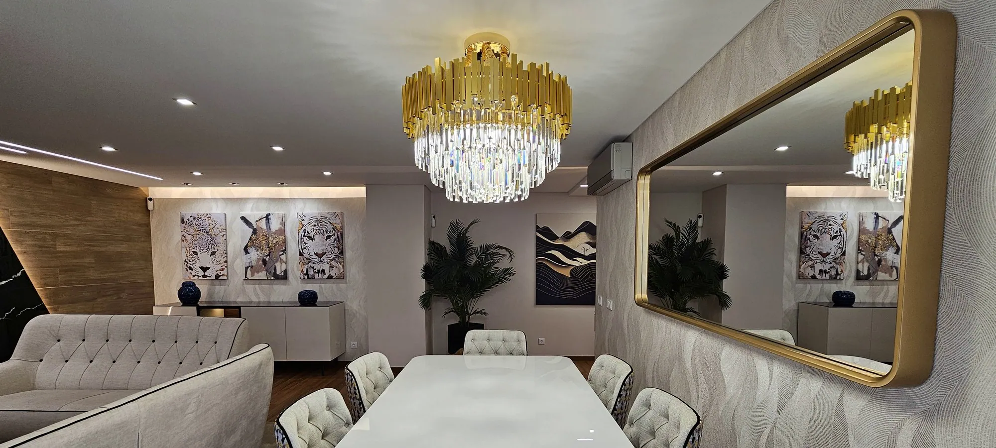 Mesa de jantar comprida sob o candeeiro de cristal e dourado.