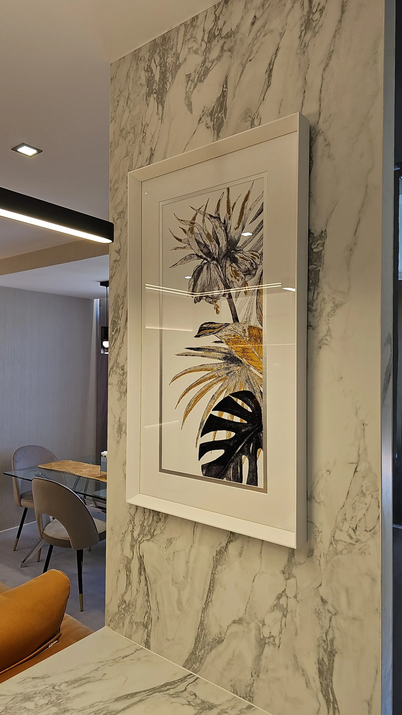Painel em pedra clara de veio com um quadro, junto à mesa.