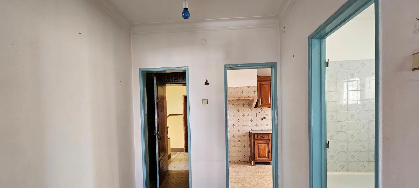 A entrada antes, com portas pintadas de azul e soalho em espinha.