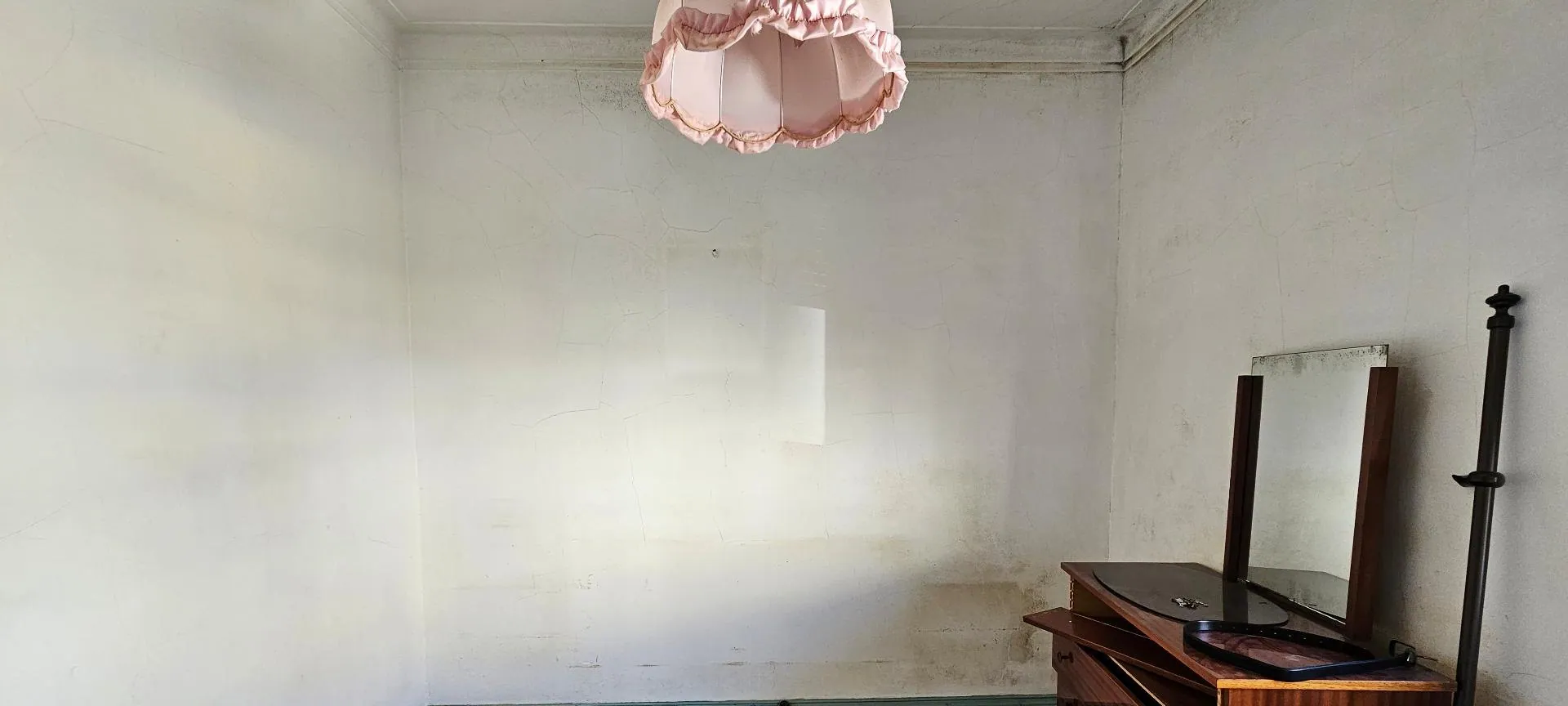 O quarto antes, com paredes manchadas e uma cómoda antiga.