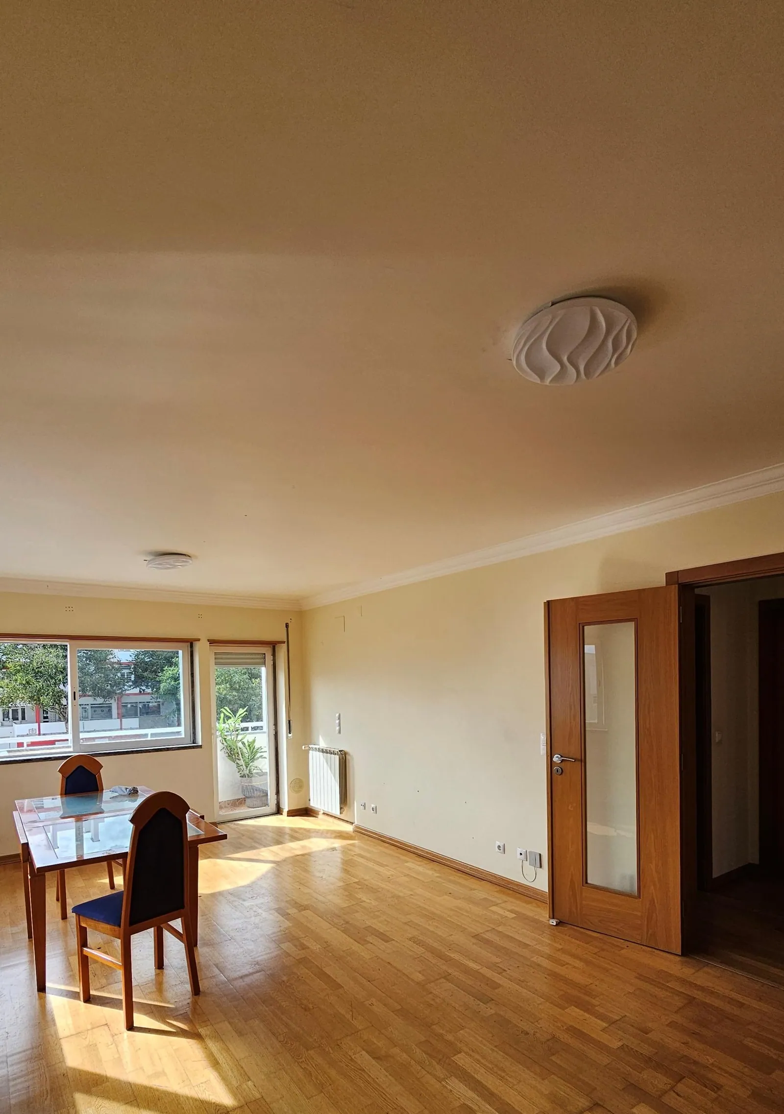 A sala antes, com soalho de madeira e mesa junto à janela.