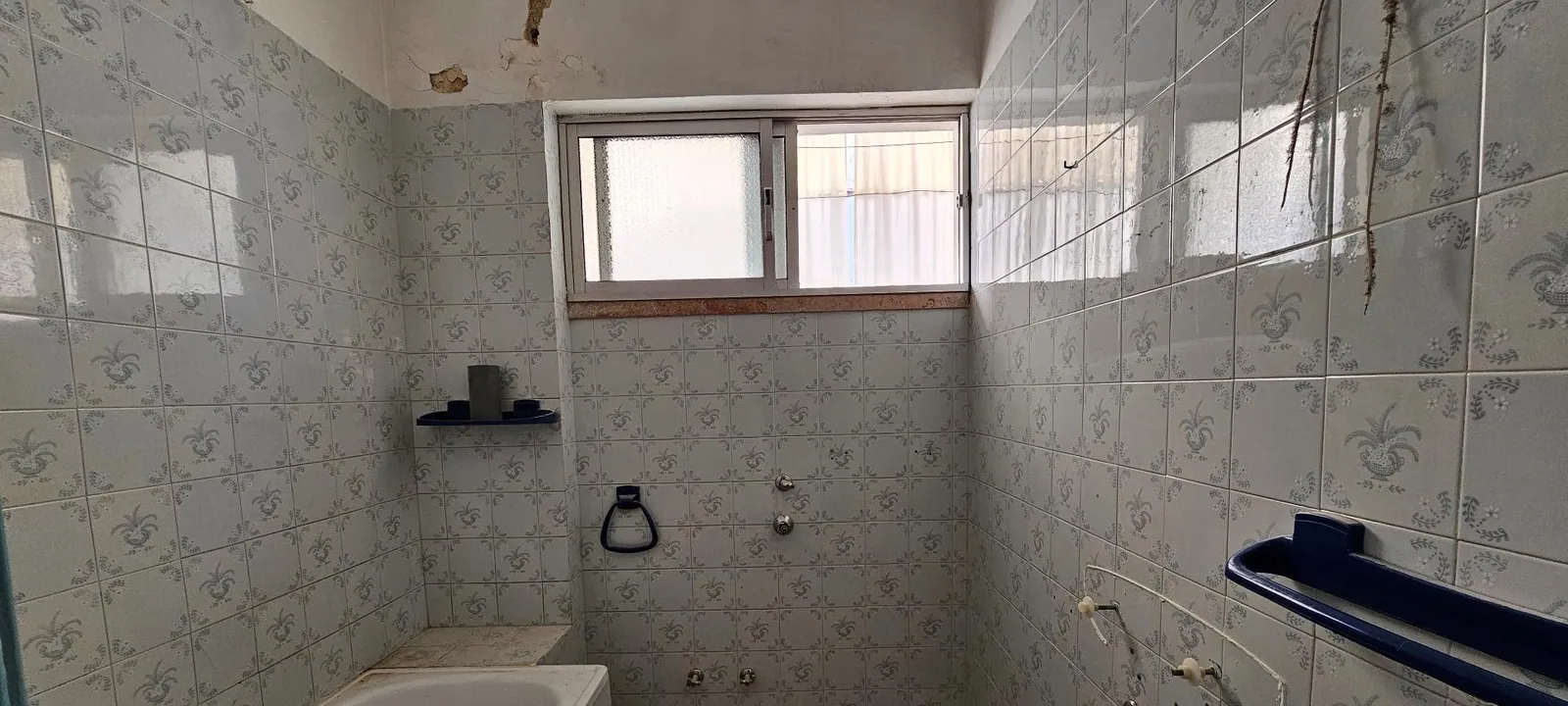A casa de banho antes, com azulejo antigo e banheira.