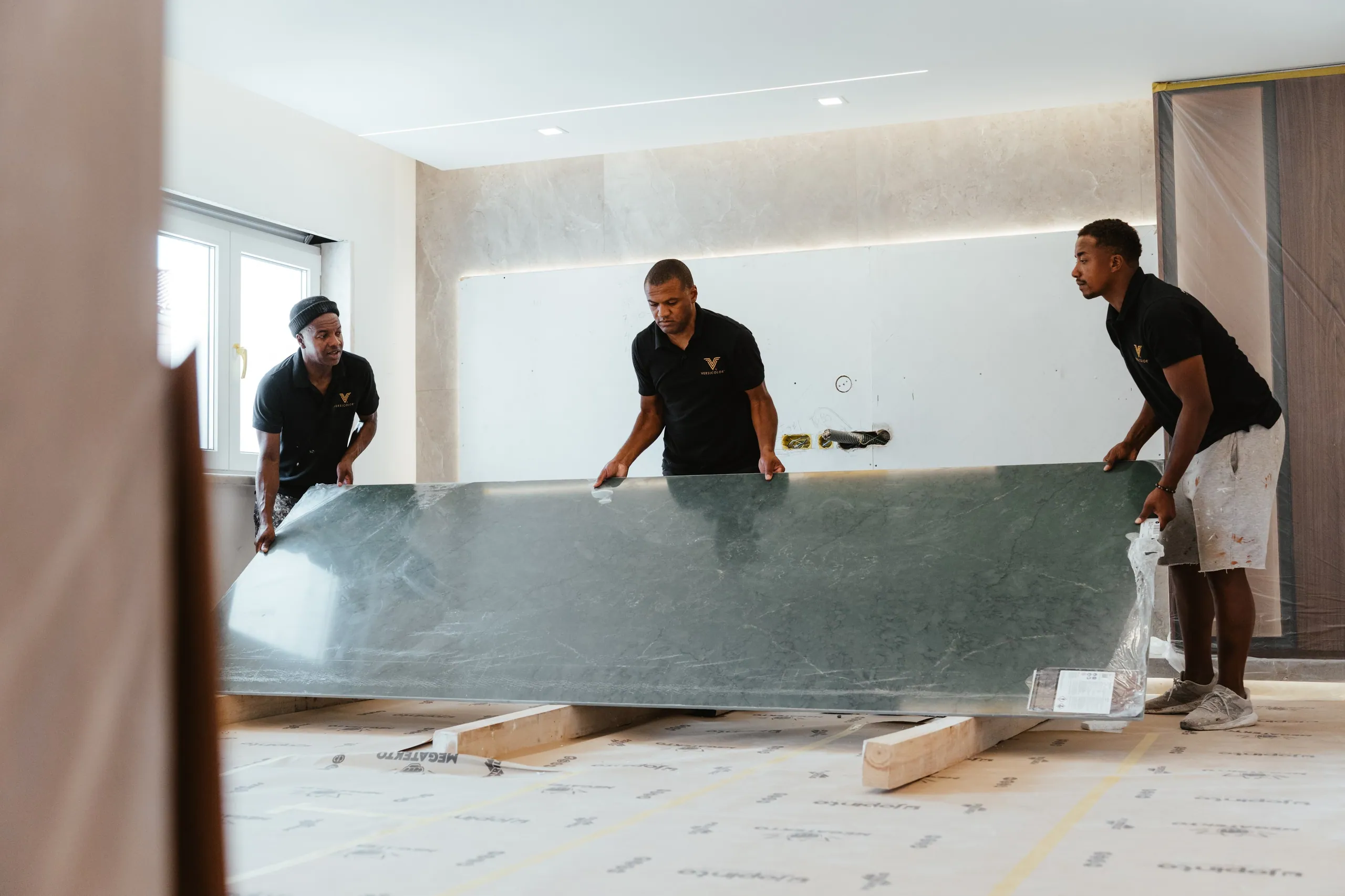 Três elementos da equipa a pousar uma placa de pedra verde escura.