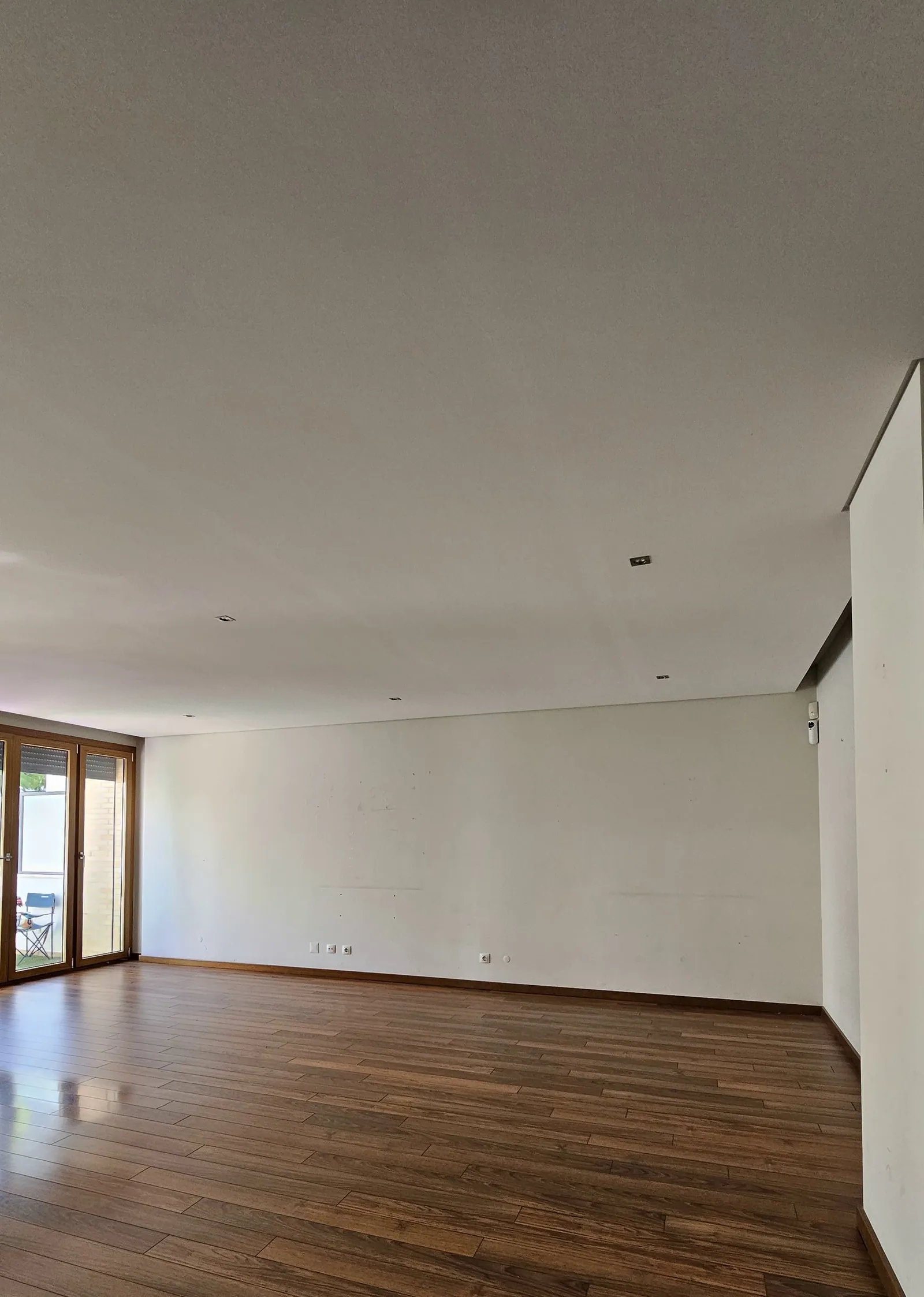 A sala antes, vazia, com soalho de madeira escura.