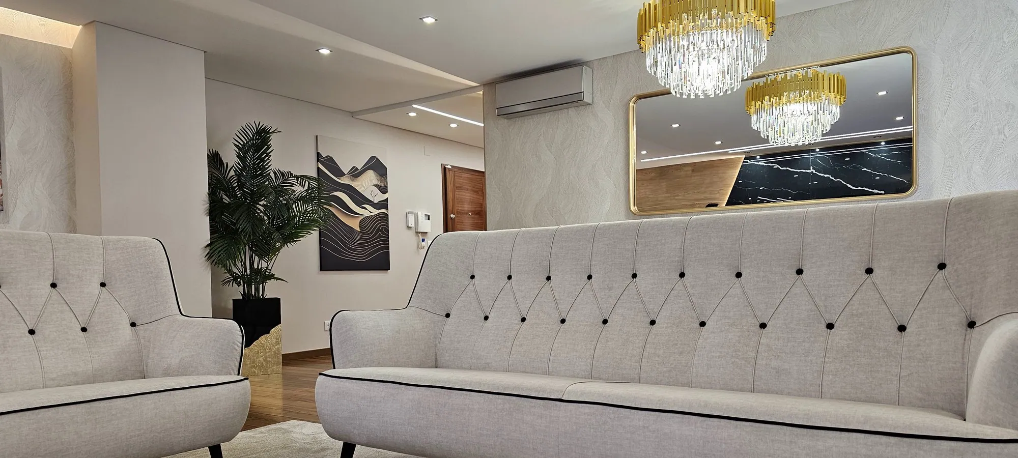 Sala com dois sofás capitonê claros.