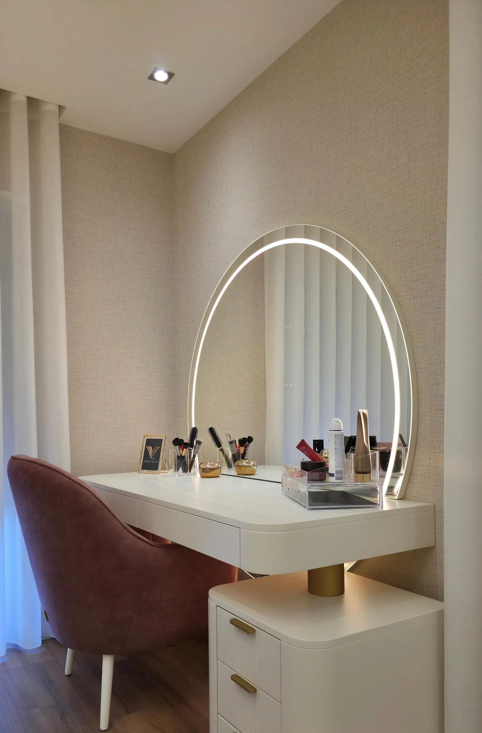 Toucador branco com espelho em arco iluminado e cadeira em veludo rosa.